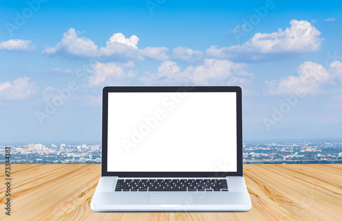Blank screen laptop computer on wood floor with blue sky backgro © littlestocker