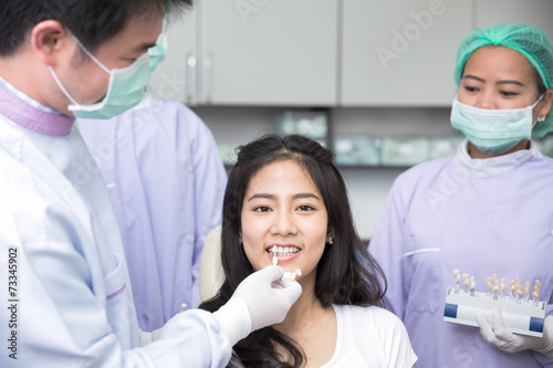 Dentist comparing patient s teeth shade