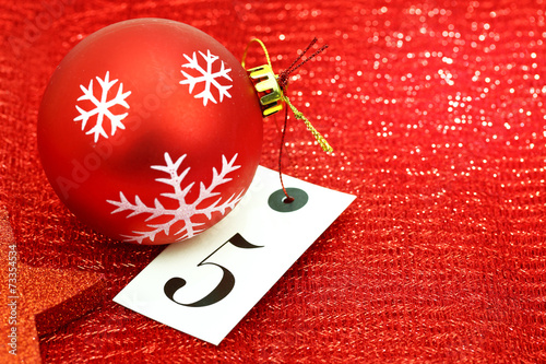 Number five on tag and Christmas ornamets on red background photo