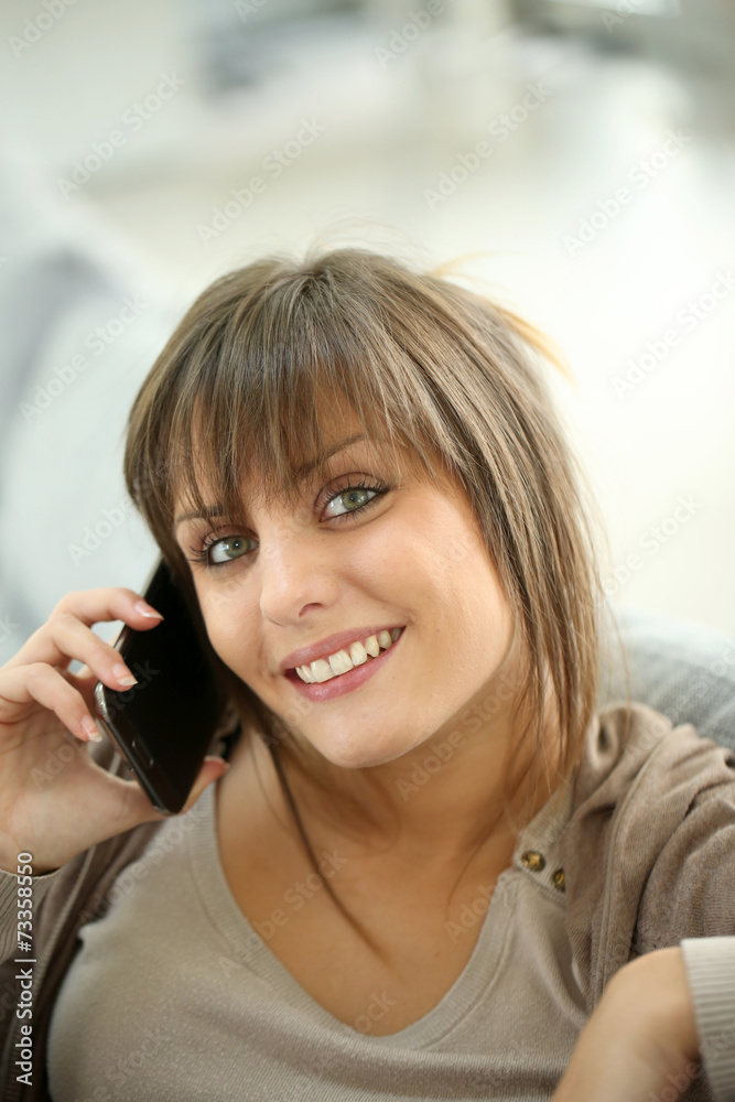 Fototapeta premium Portrait of young woman at home talking on mobile phone
