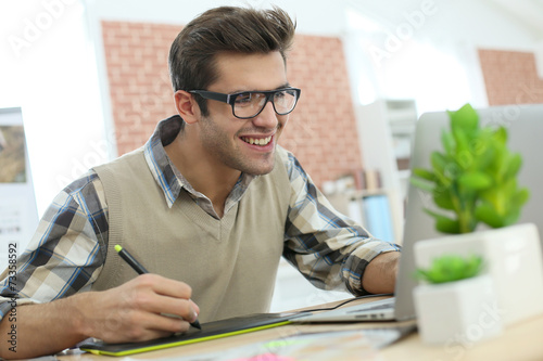Young man in office using graphic tablet