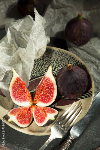 fresh figs on a ceramic plate, fork and knife, with white paper