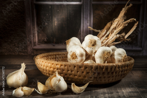 Organic garlic in a straw basket in a dark background
