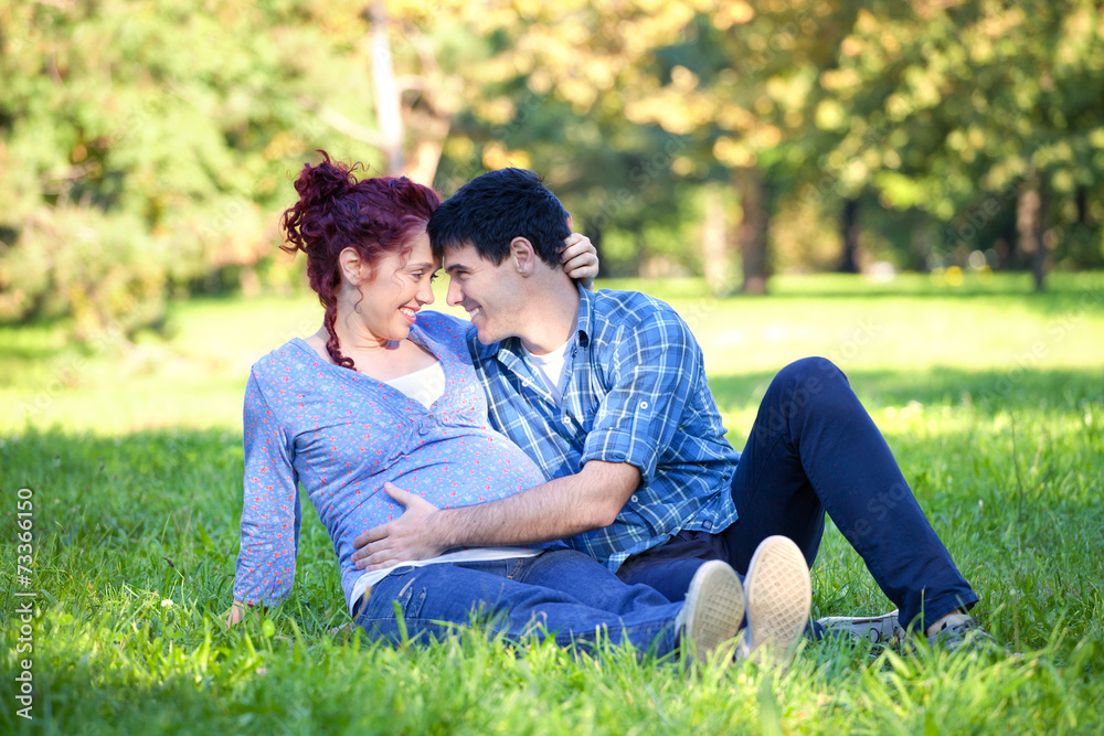 Pregnant couple relaxing in autumn park Pregnant couple relaxing in autumn park