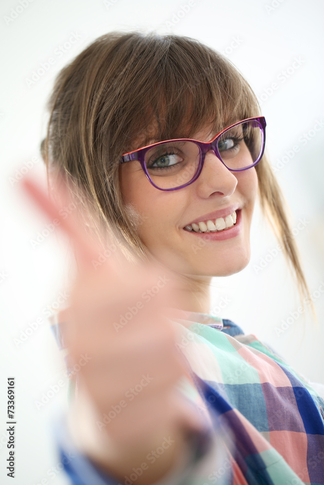 Cheerful girl with eyeglasses showing thumb up Cheerful girl with eyeglasses showing thumb up