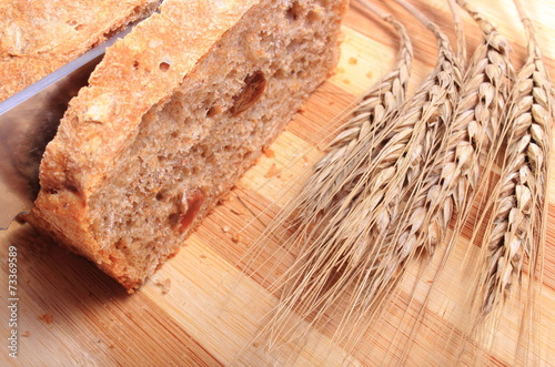 Slicing fresh bread, ears of wheat