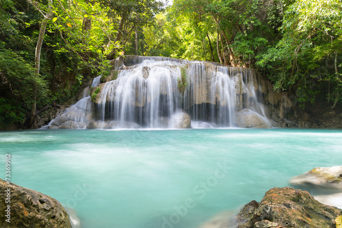 Waterfall, green forest in Erawan National Park, Thailand. Landscape with water flow, river, stream and rock at outdoor. Beautiful scenery of nature for tourist to tour, visit, relax in vacation.