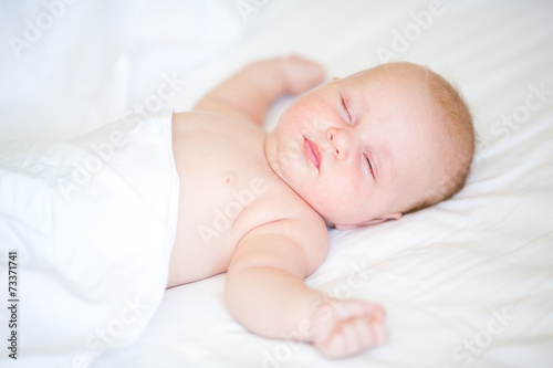 Peaceful newborn baby lying on a bed sleeping