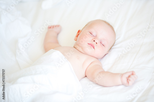 Peaceful newborn baby lying on a bed sleeping