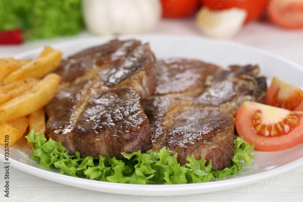 Steaks vom Schwein Fleisch Gericht mit Pommes, Gemüse und Salat Steaks vom Schwein Fleisch Gericht mit Pommes, Gemüse und Salat