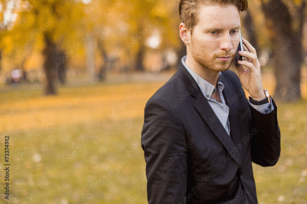 Young man with mobile phone in the autumn park Young man with mobile phone in the autumn park