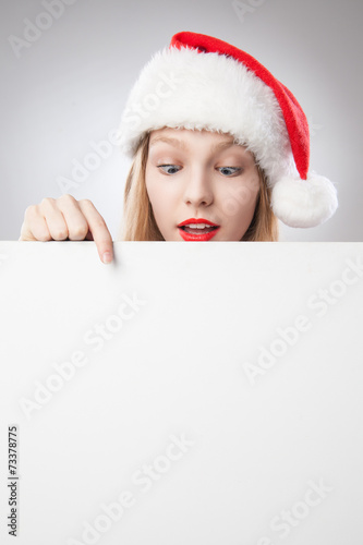 Christmas woman in santa hat pointing empty board