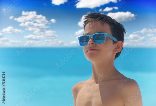 Portrait of young boy wearing sunglasses and posing by sea