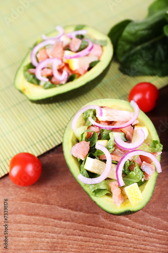 Tasty salad in avocado on table and bamboo napkin close-up