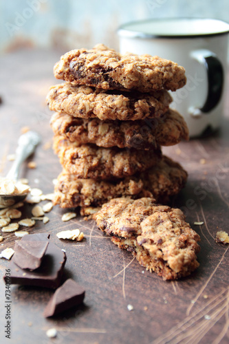 Stack of oat cookies with chocolate and mug of milk