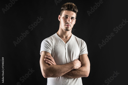 Portrait of confident young man wearing white shirt with crossed