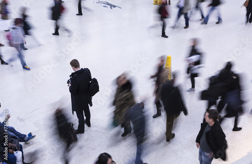 Unrecognised man stands still whilst people move around him