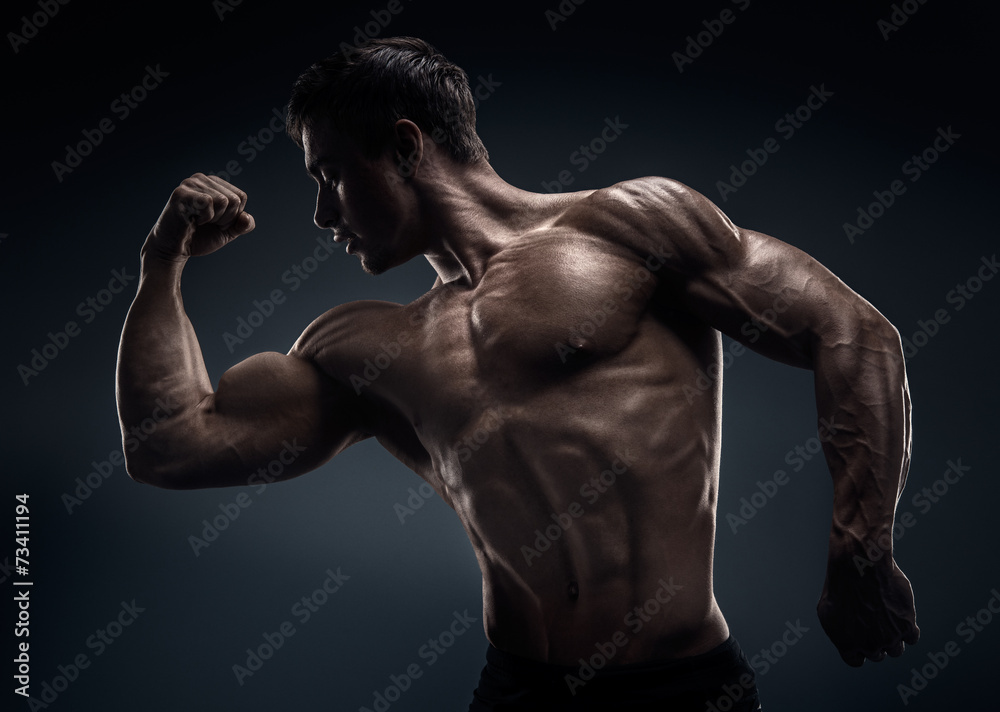 Handsome muscular bodybuilder posing over black background