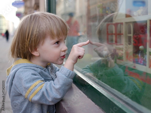 Boy pointing a favorite toy through the showcase