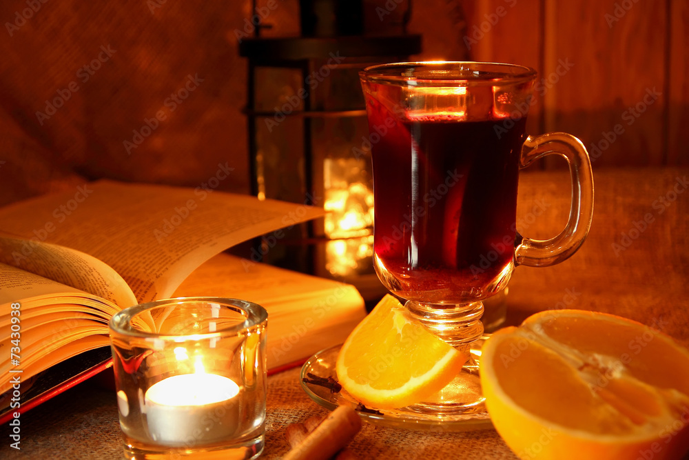 Hot mulled wine in the cup and open book..