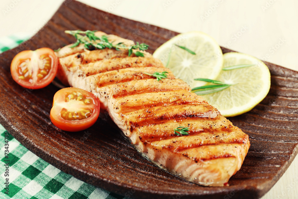 Grilled salmon and vegetables on plate on wooden background Grilled salmon and vegetables on plate on wooden background