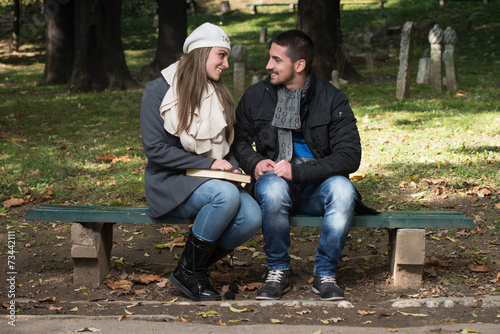 Young Romantic Couple In Park And Reading Book