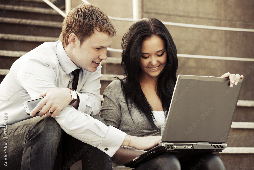 Young business couple using laptop outdoor