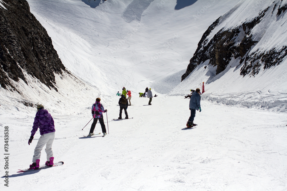 Skiers and snowboarders going down the slope.