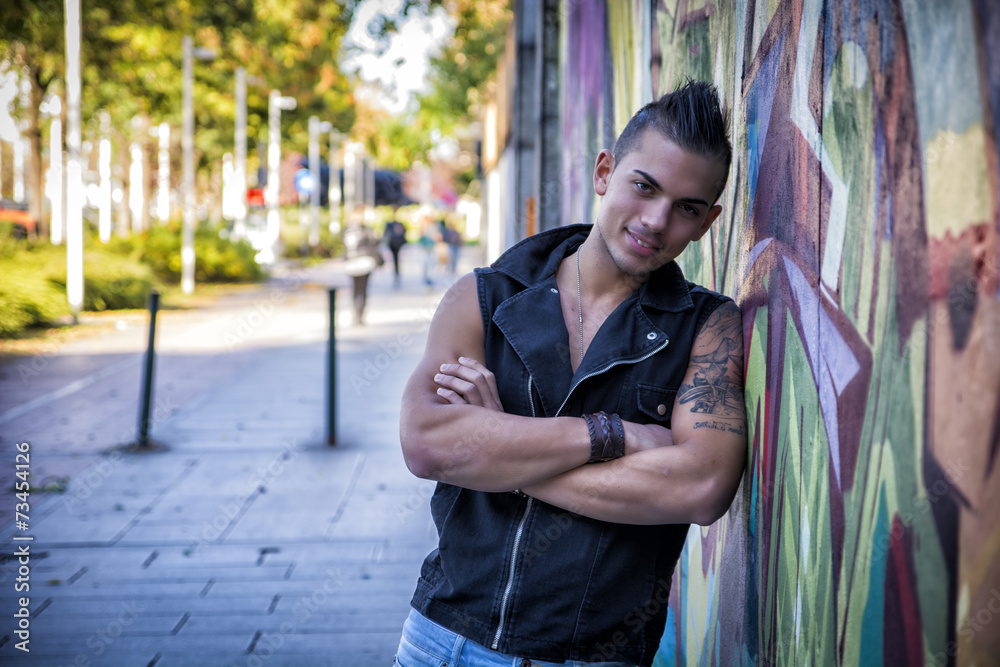 Handsome young man against colorful graffiti wall