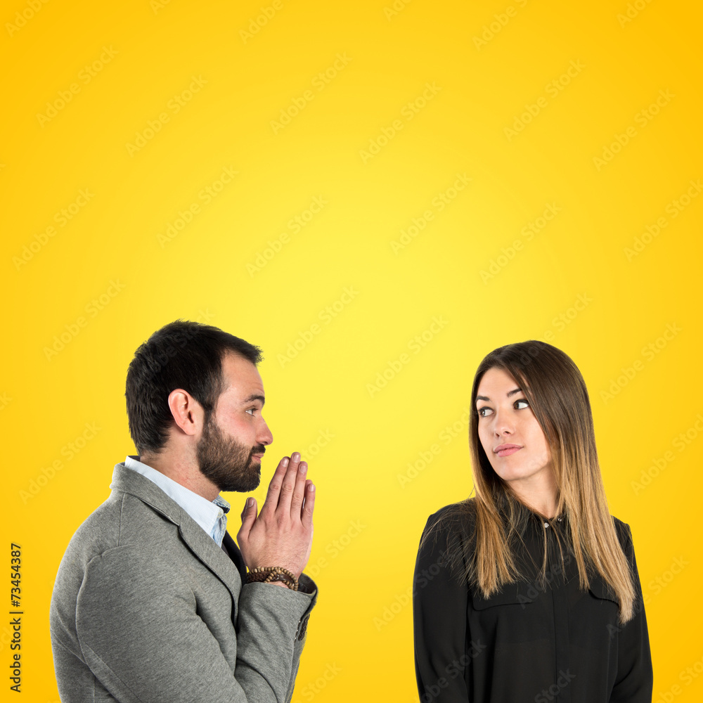 Men pleading at his girlfriend over yellow background Men pleading at his girlfriend over yellow background