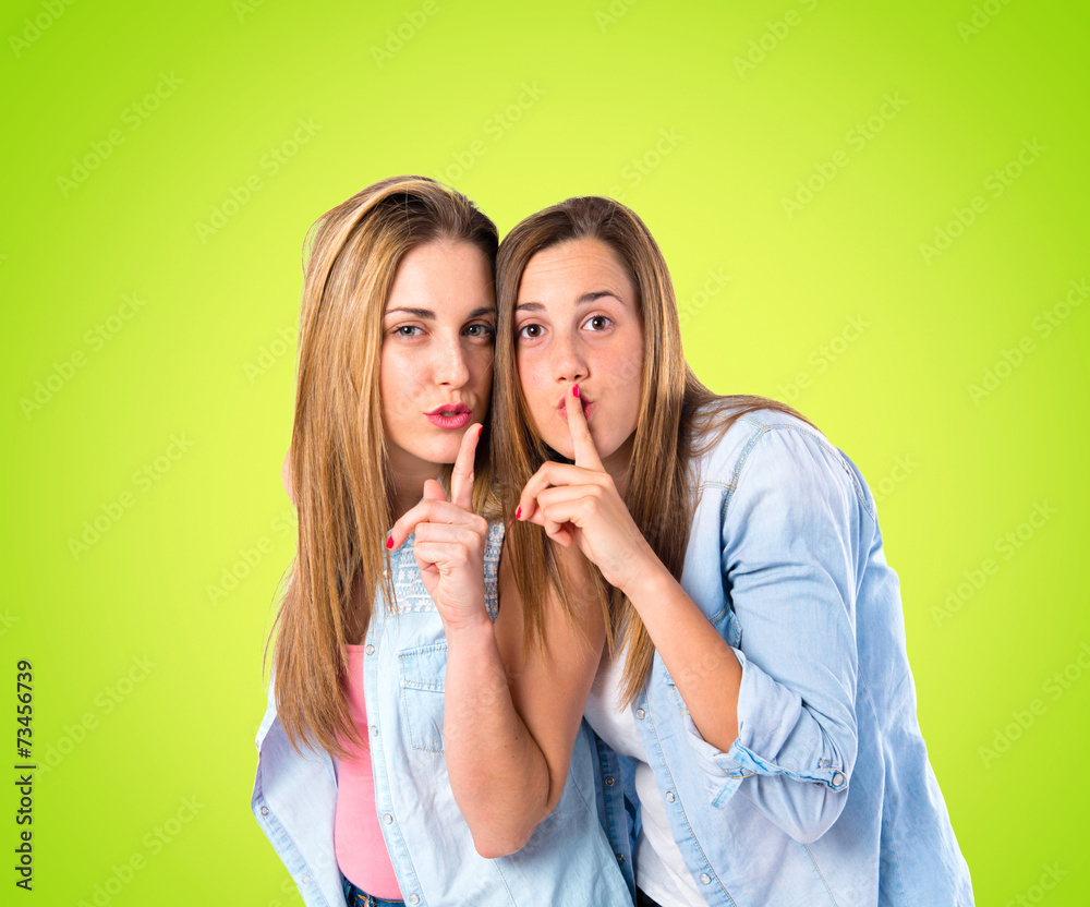 Friends making silence gesture over green background Friends making silence gesture over green background