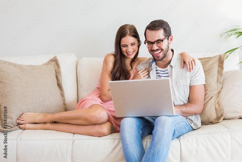 Hipster couple using laptop on couch