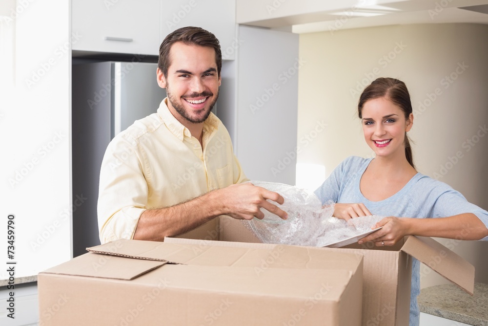 Young couple unpacking boxes in kitchen Young couple unpacking boxes in kitchen