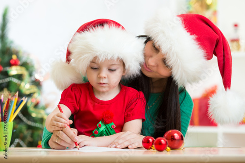Child girl and mom writing ...