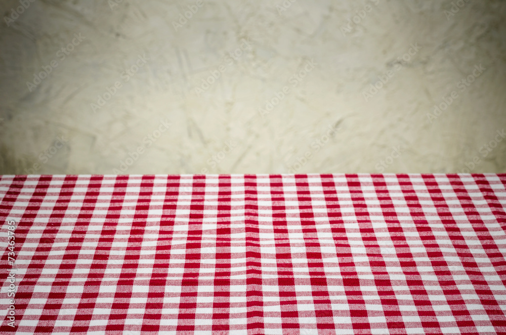 Rot-weiß kariertes Tischtuch vor rustikaler Wand