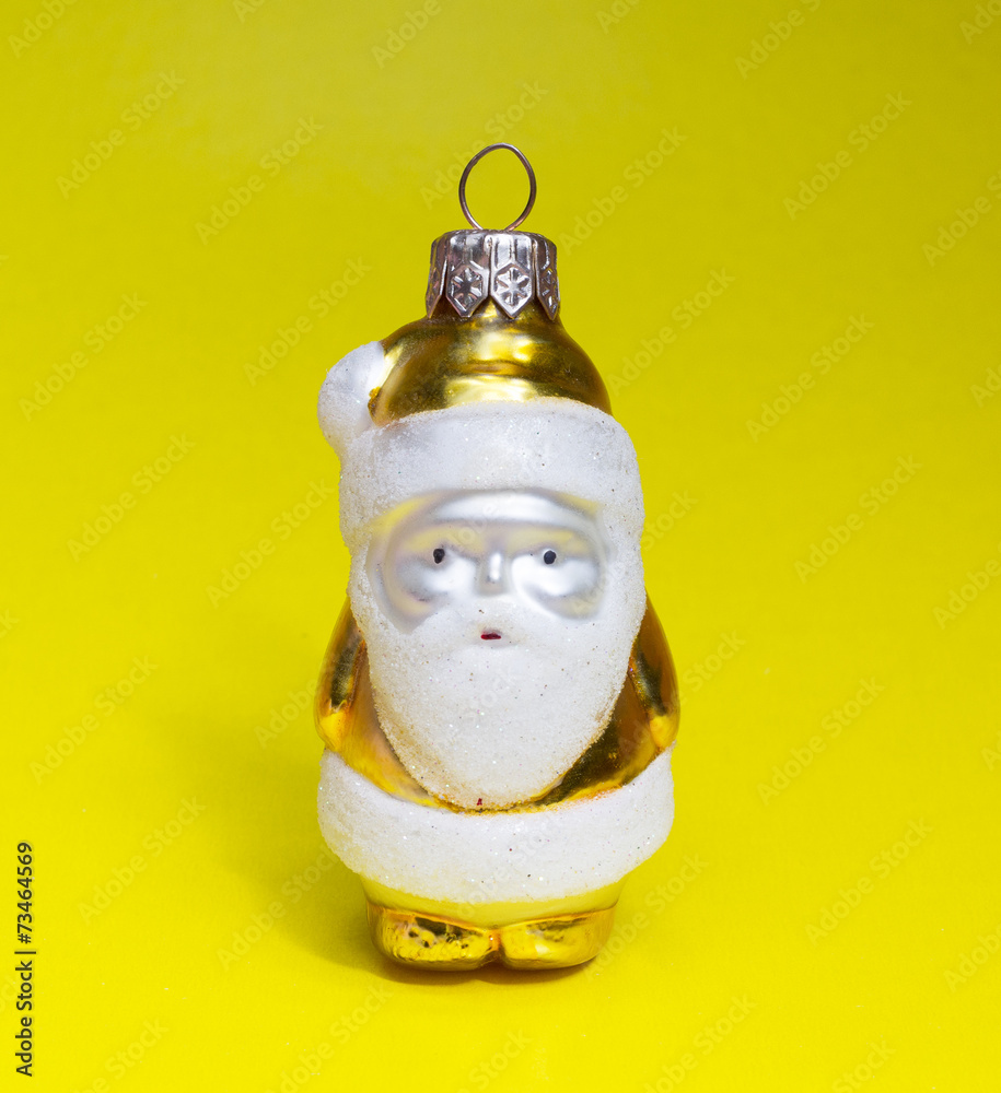 Yellow toy Santa on yellow background