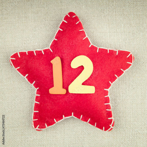 Red star with wooden number 12 on vintage fabric background