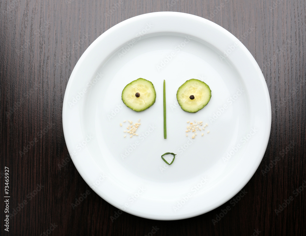 Vegetable face on plate on wooden table Vegetable face on plate on wooden table
