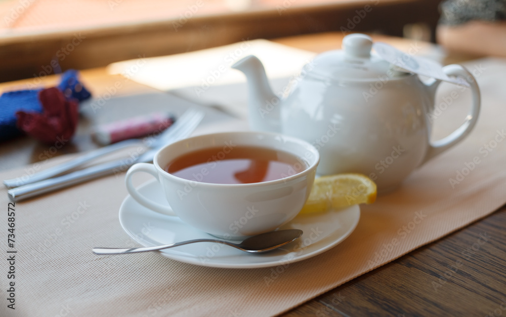 Obraz premium Cup of tea with lemon and teapot