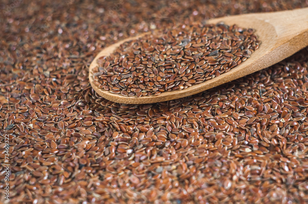 flax seeds with a wooden spoon on burlap background flax seeds with a wooden spoon on burlap background