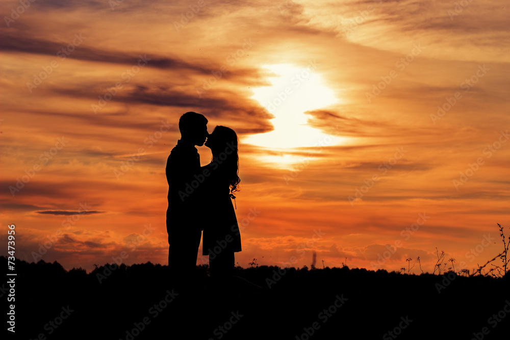 loving happy couple kissing at sunset in a field