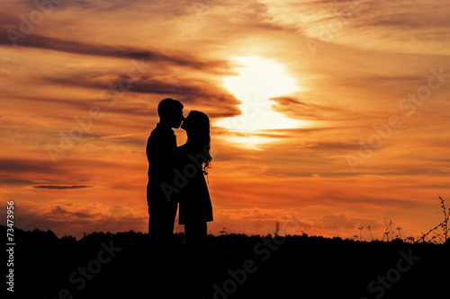 loving happy couple kissing at sunset in a field