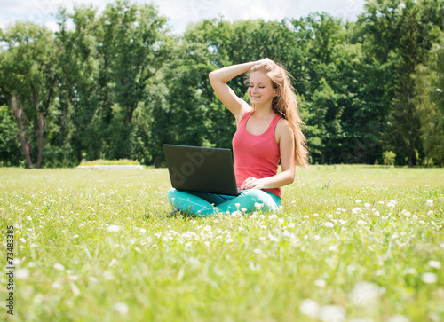 Beautiful casual female student  outdoor using pc. © Polina Ponomareva