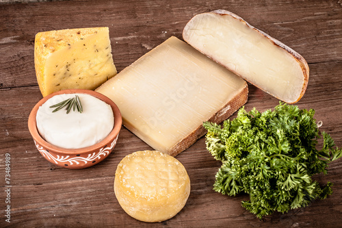 Various types of cheese on a wooden background with parsley.Tint