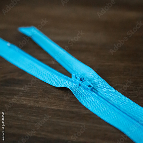 Blue zipper on dark wood background