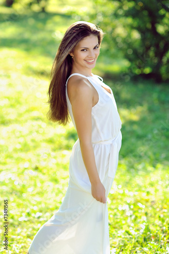 Beautiful girl in white dress walking on a meadow