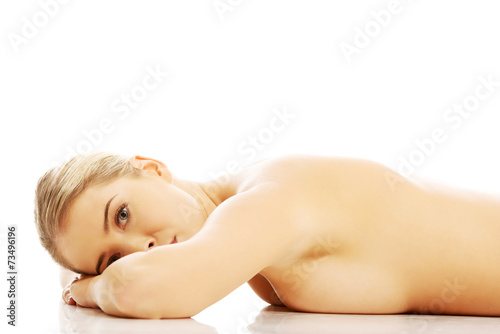 Side view of a nude woman lying on the floor