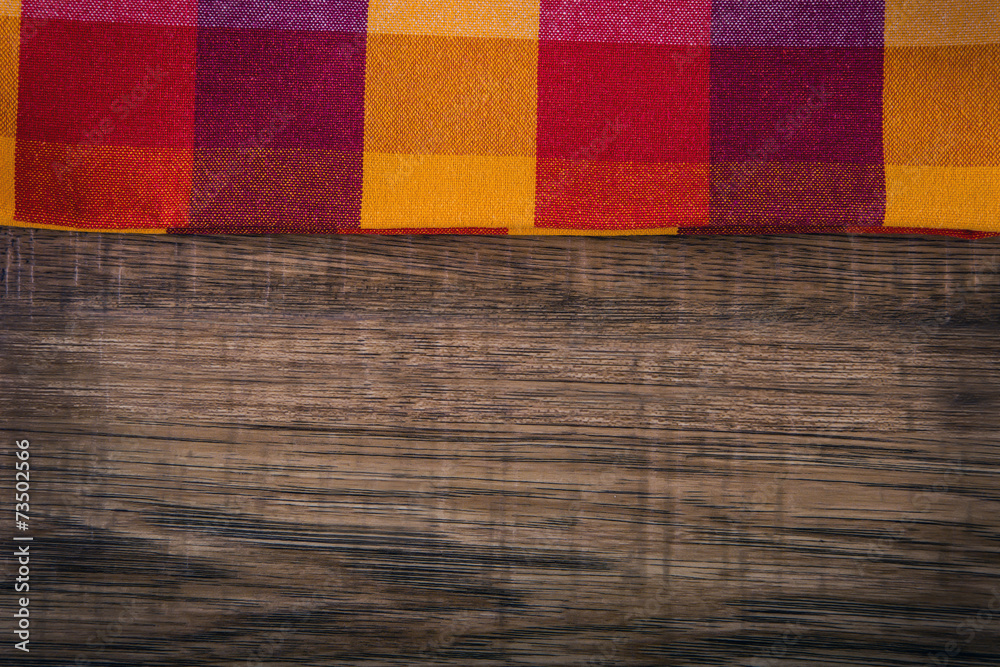 Fototapeta premium Top view of checkered napkin on empty wooden table