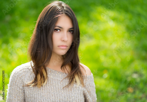 Portrait of young woman in sweater. Green bokeh background.