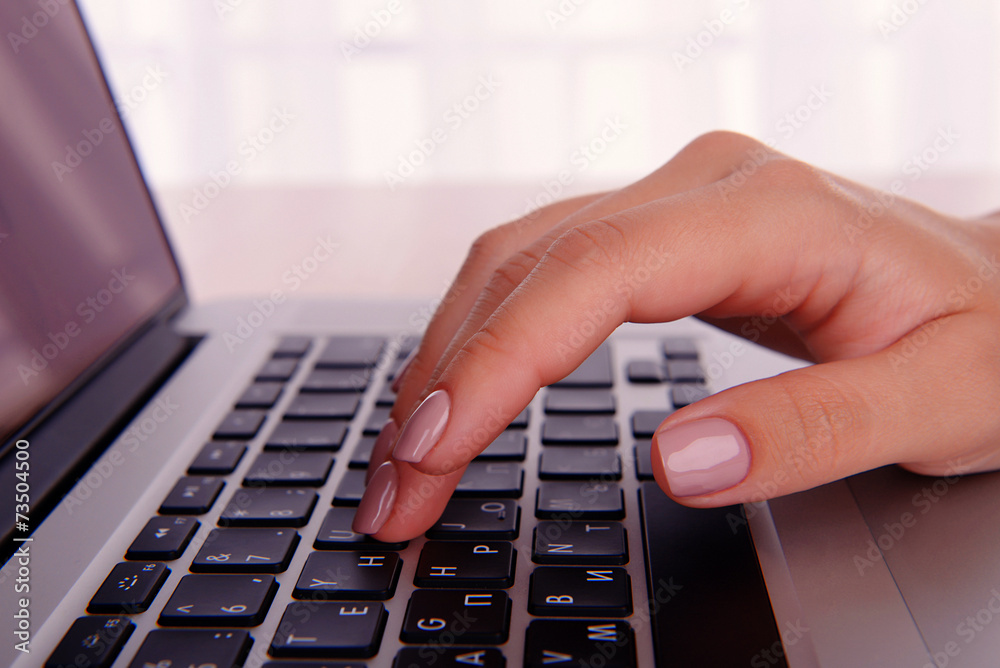Female hands working on laptop on light background